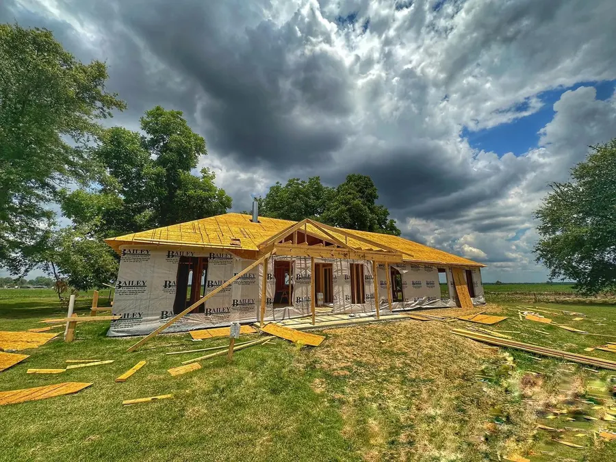 Custom home framing and roof decking going up under a dramatic sky in Belzoni, Mississippi