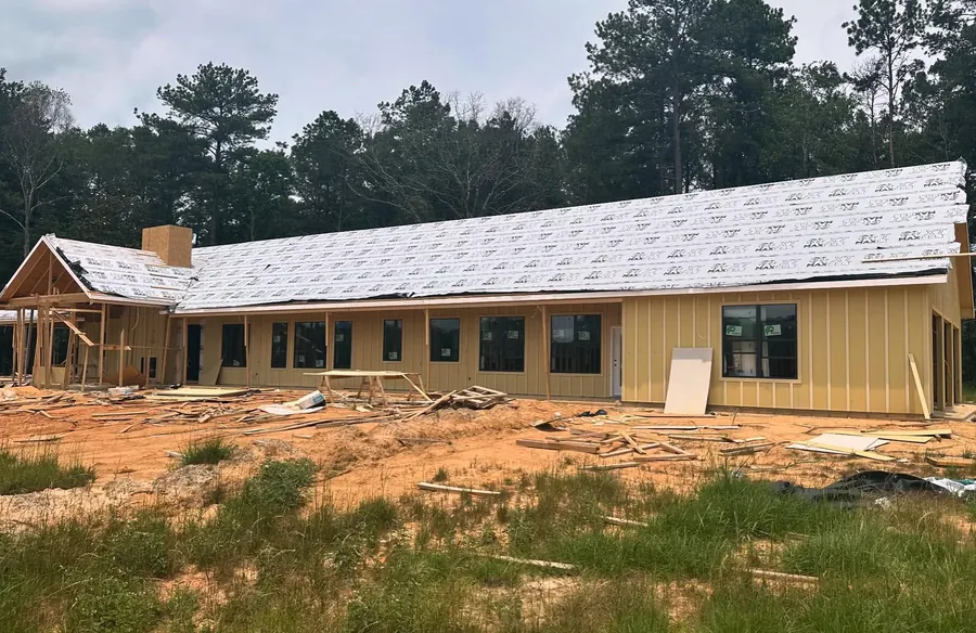 Long custom home under construction with house wrap and a new roof deck in Bogue Chitto, Mississippi