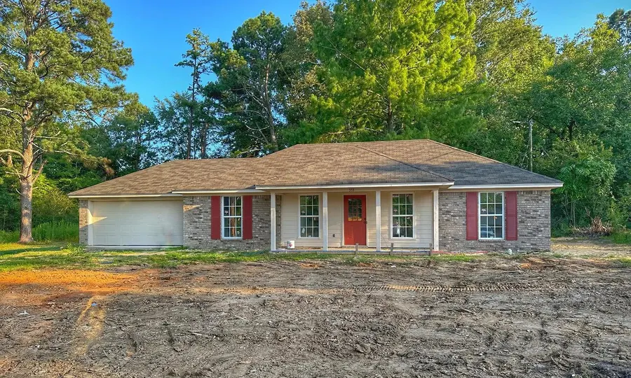 Brick ranch home with a red front door and attached garage in Forest, Mississippi