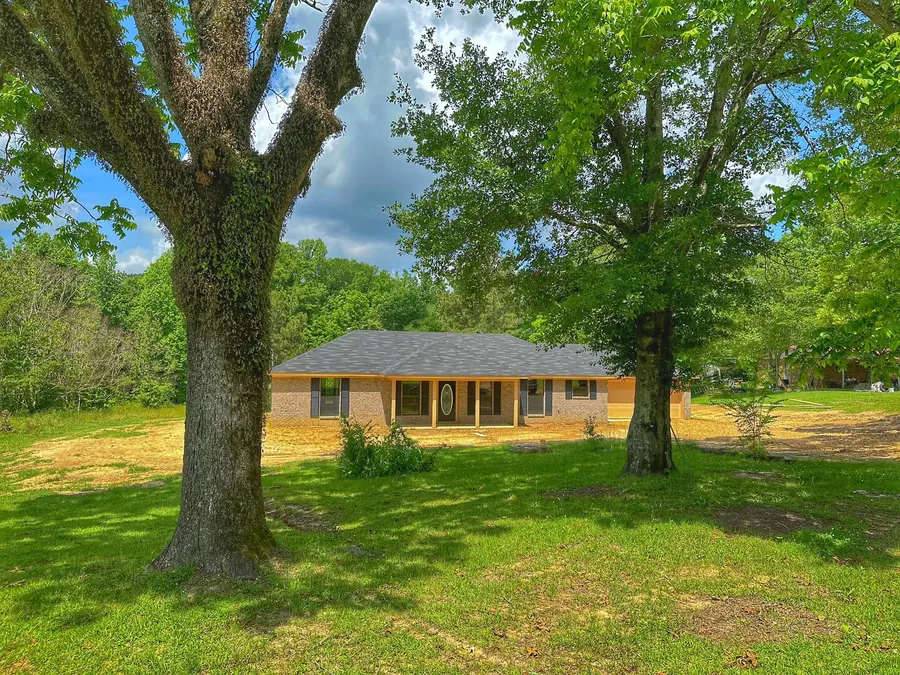 New brick ranch home set back behind two large pecan trees in Terry, Mississippi
