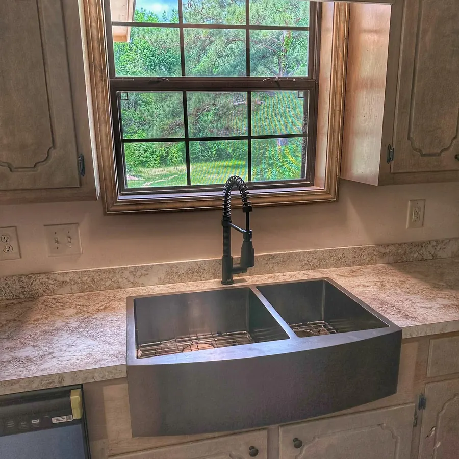 Stainless farmhouse sink under a window looking out on green trees in Terry, Mississippi