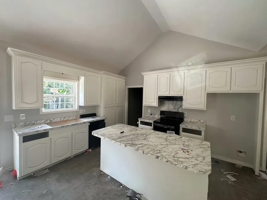 Vaulted-ceiling kitchen with white cabinets and a marble-look island